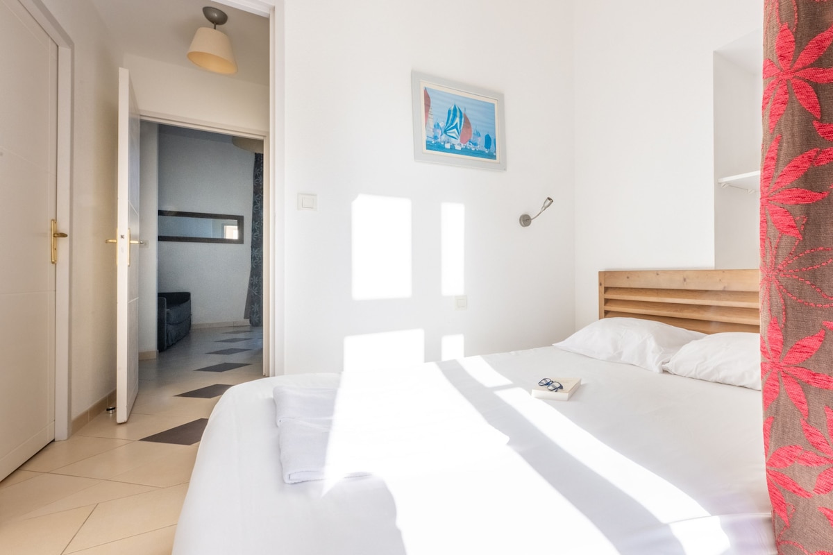 Une chambre à coucher avec un lit, une porte, un couloir et un tableau accroché au mur.