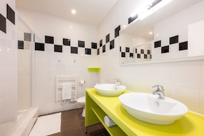 Une salle de bain moderne avec deux lavabos, une douche et des toilettes.