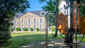 Ein Spielplatz mit einer Metallkonstruktion, umgeben von einer Rasenfläche und einem Gebäude mit vielen Fenstern im Hintergrund.