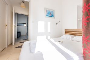 Une chambre à coucher avec un lit, une porte, un couloir et un tableau accroché au mur.