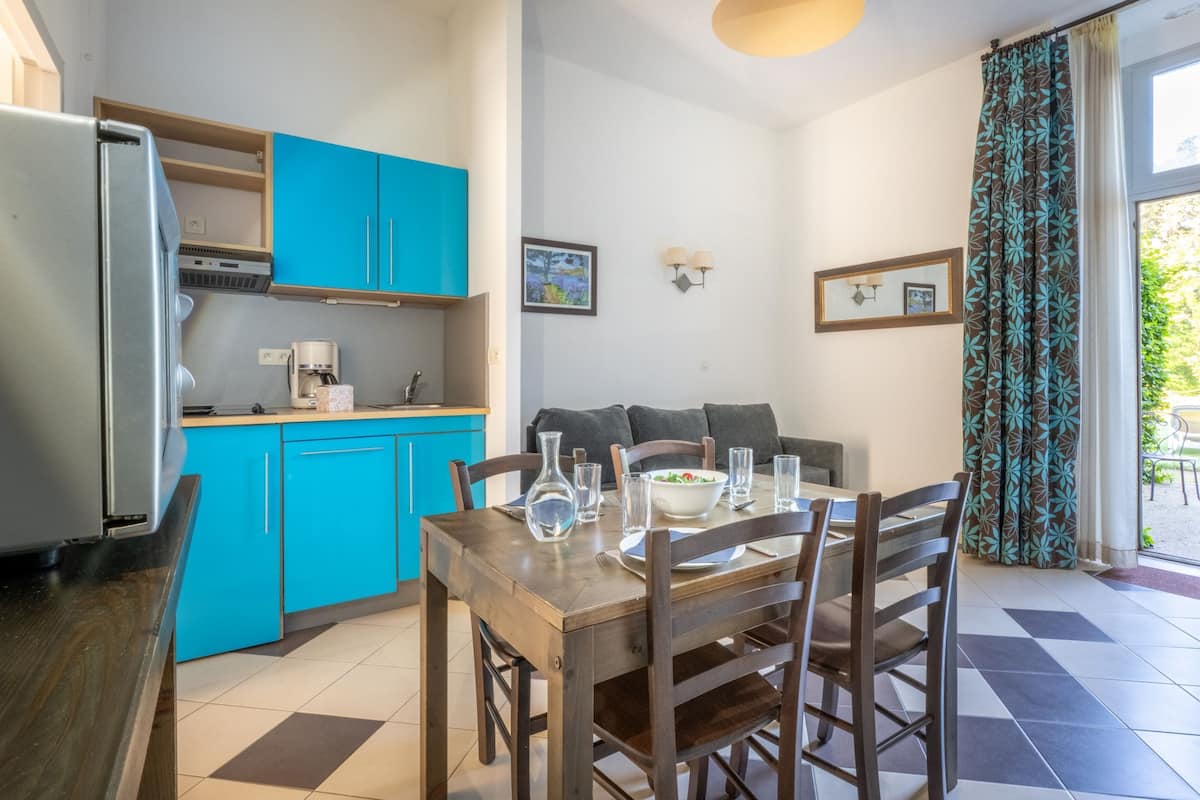 Una cocina compacta con refrigerador, cafetera y armarios azules.