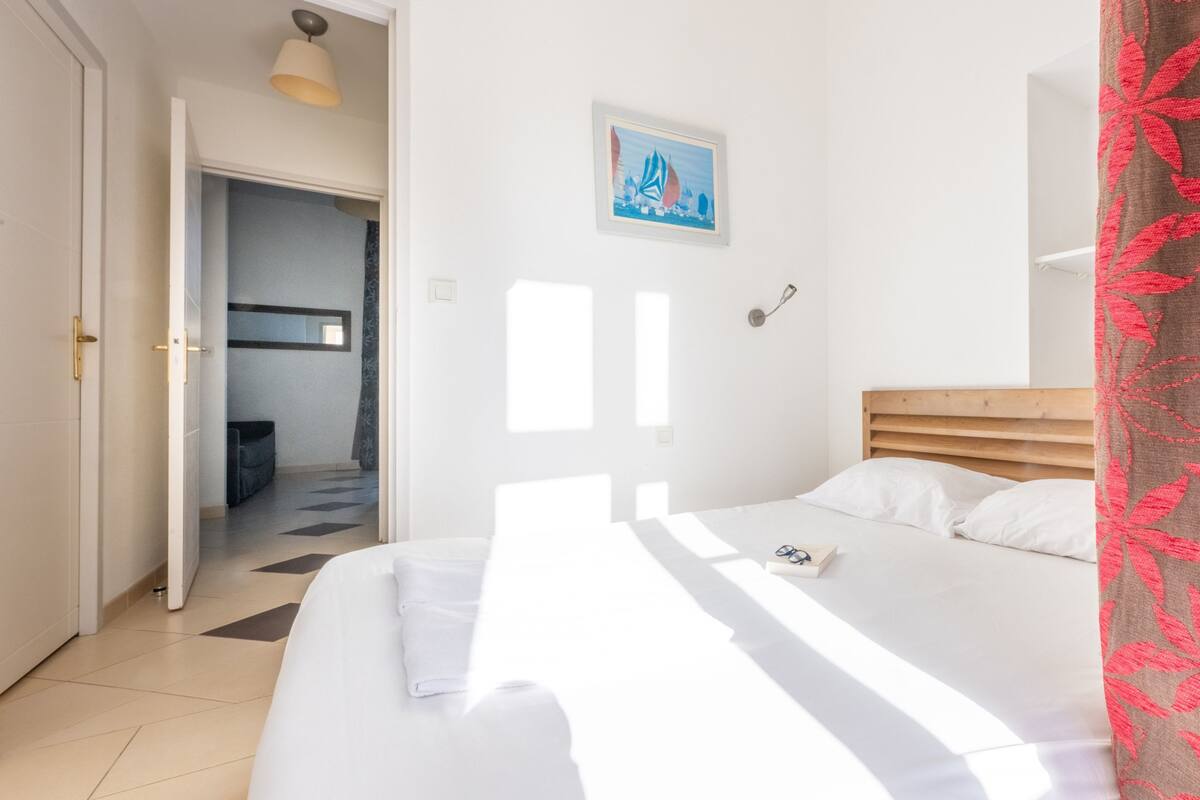 Un dormitorio con una cama, una puerta, un pasillo y un cuadro en la pared.