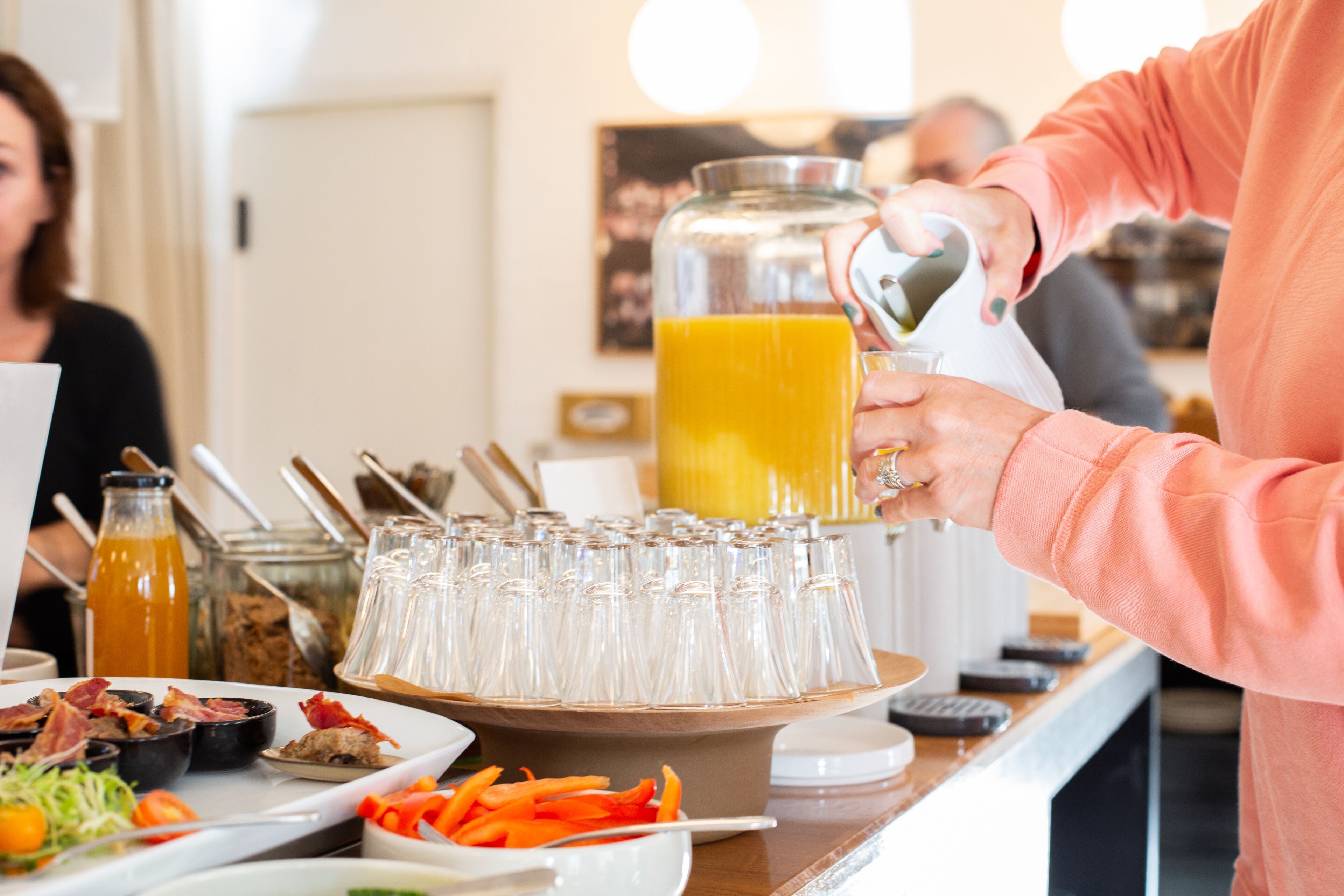 Un buffet proposant divers plats et une carafe de jus d’orange.