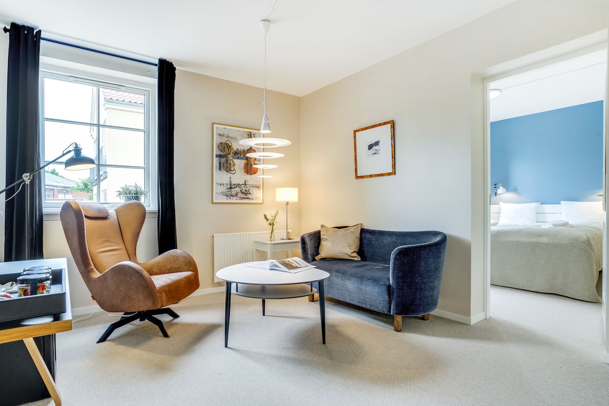 Een moderne hotelkamer met een bank, fauteuil en een klein tafeltje.