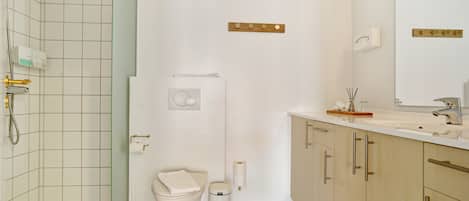 A modern bathroom with a shower, toilet, and sink.
