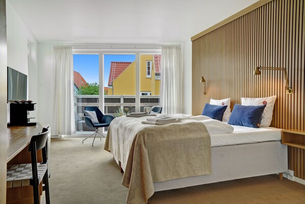 Une chambre d’hôtel avec un lit, un bureau, une chaise et une vue sur l’extérieur.