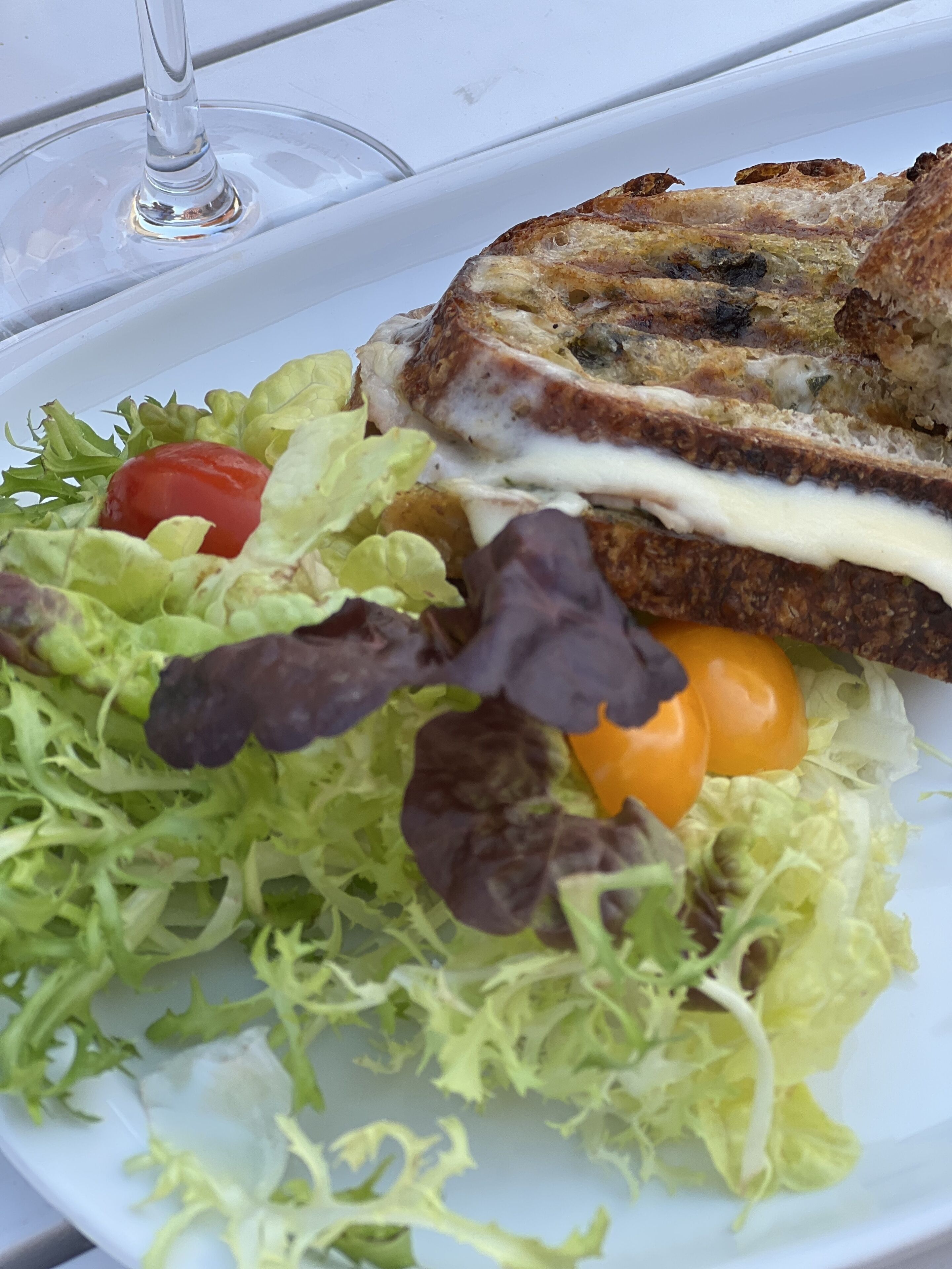 Un plato con un sándwich, ensalada y un vaso de agua.