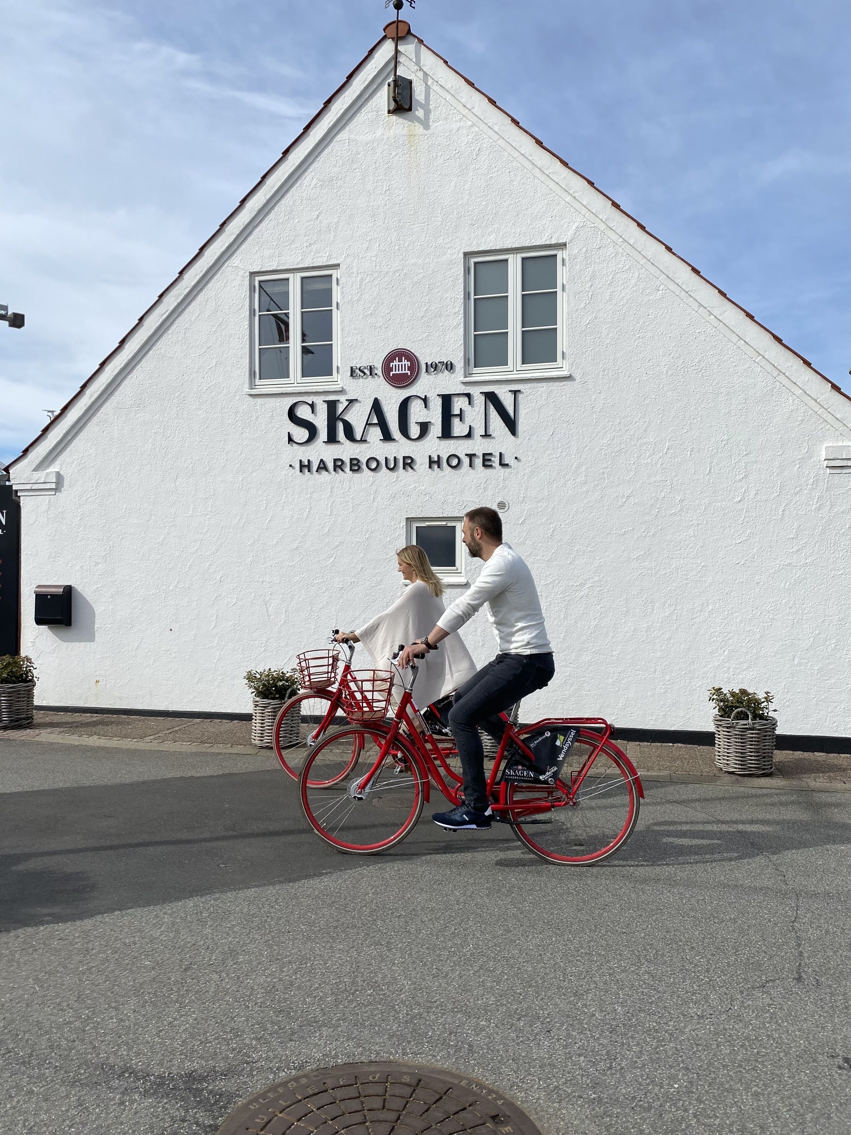 A building with the sign "SKAGEN Harbour Hotel" and a red bicycle parked in front.