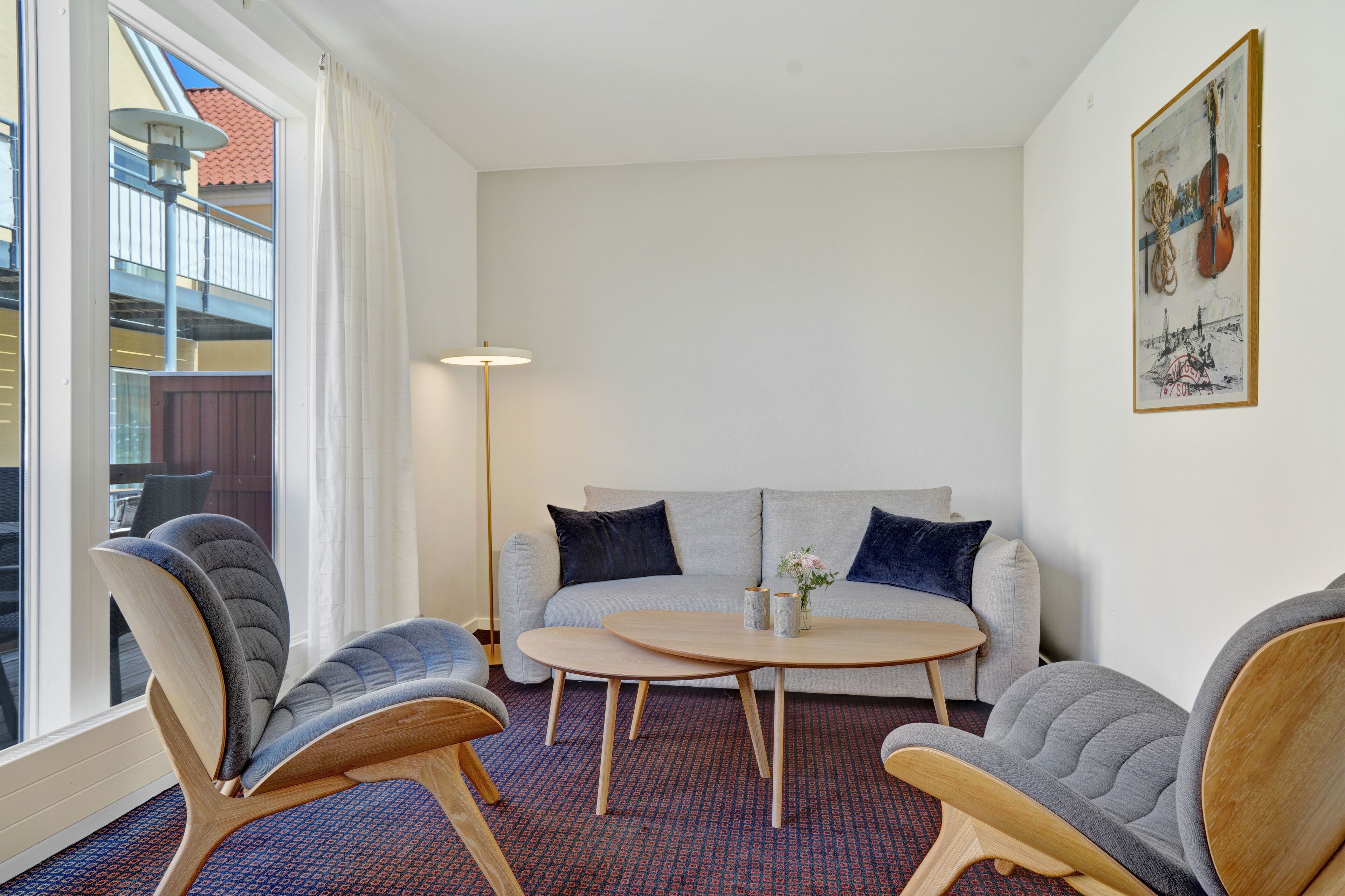 A modern living room with a sofa, two armchairs, a small round table, and a floor lamp.