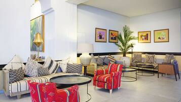 A spacious lobby with a sofa set, armchairs, a coffee table, and a potted plant.
