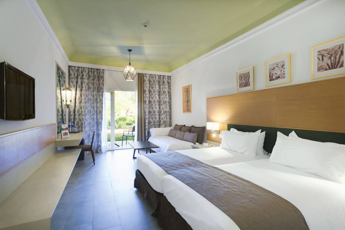 A hotel room with two beds, a TV, a desk, and a chair.