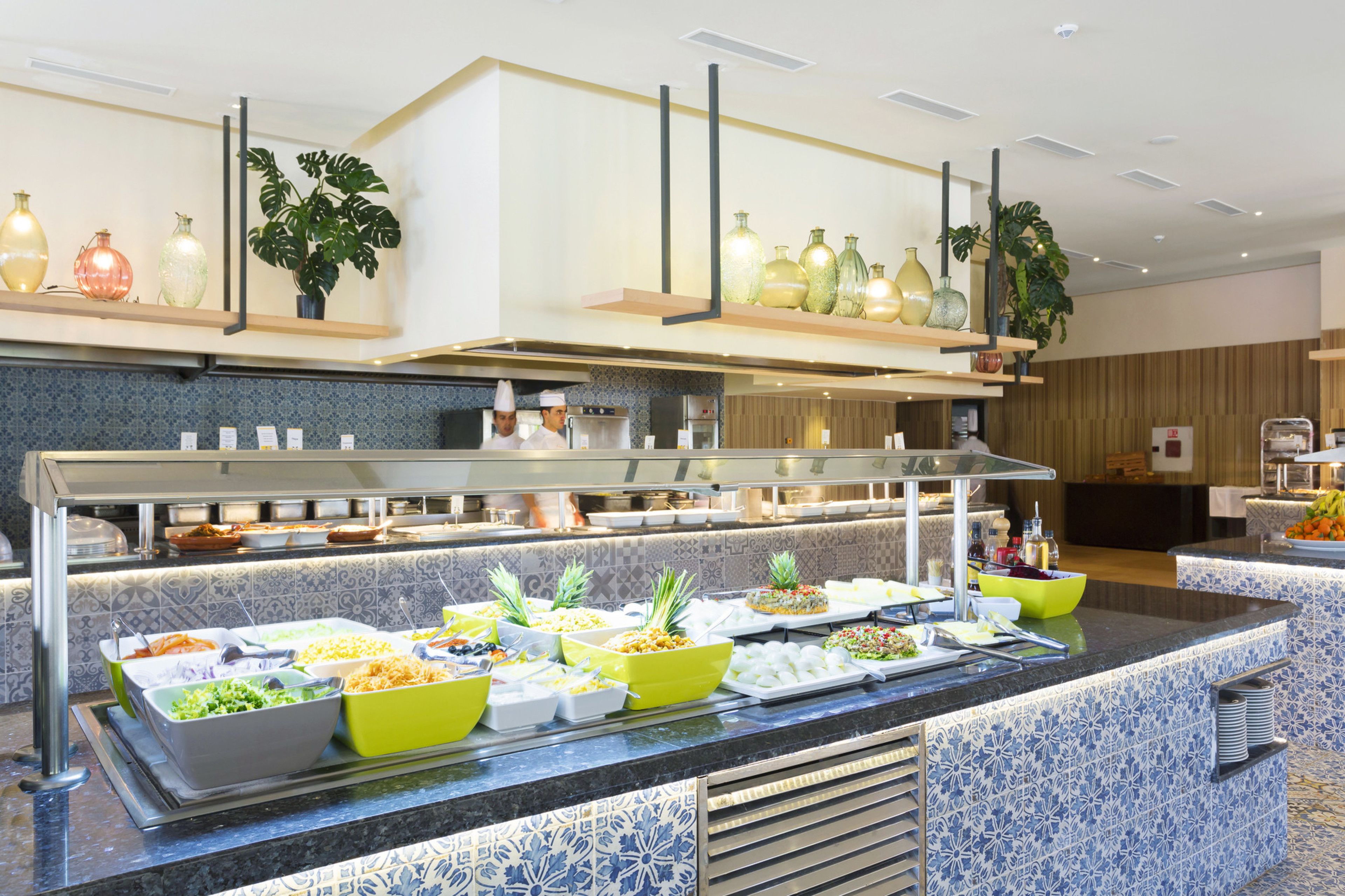 A buffet area with various food options, a chef, and a kitchen in the background.