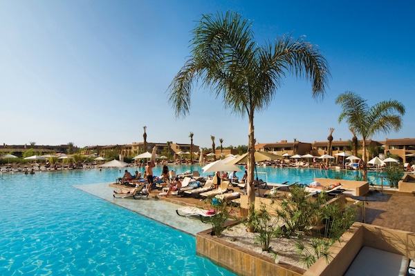 Una piscina techada, una piscina al aire libre, sombrillas