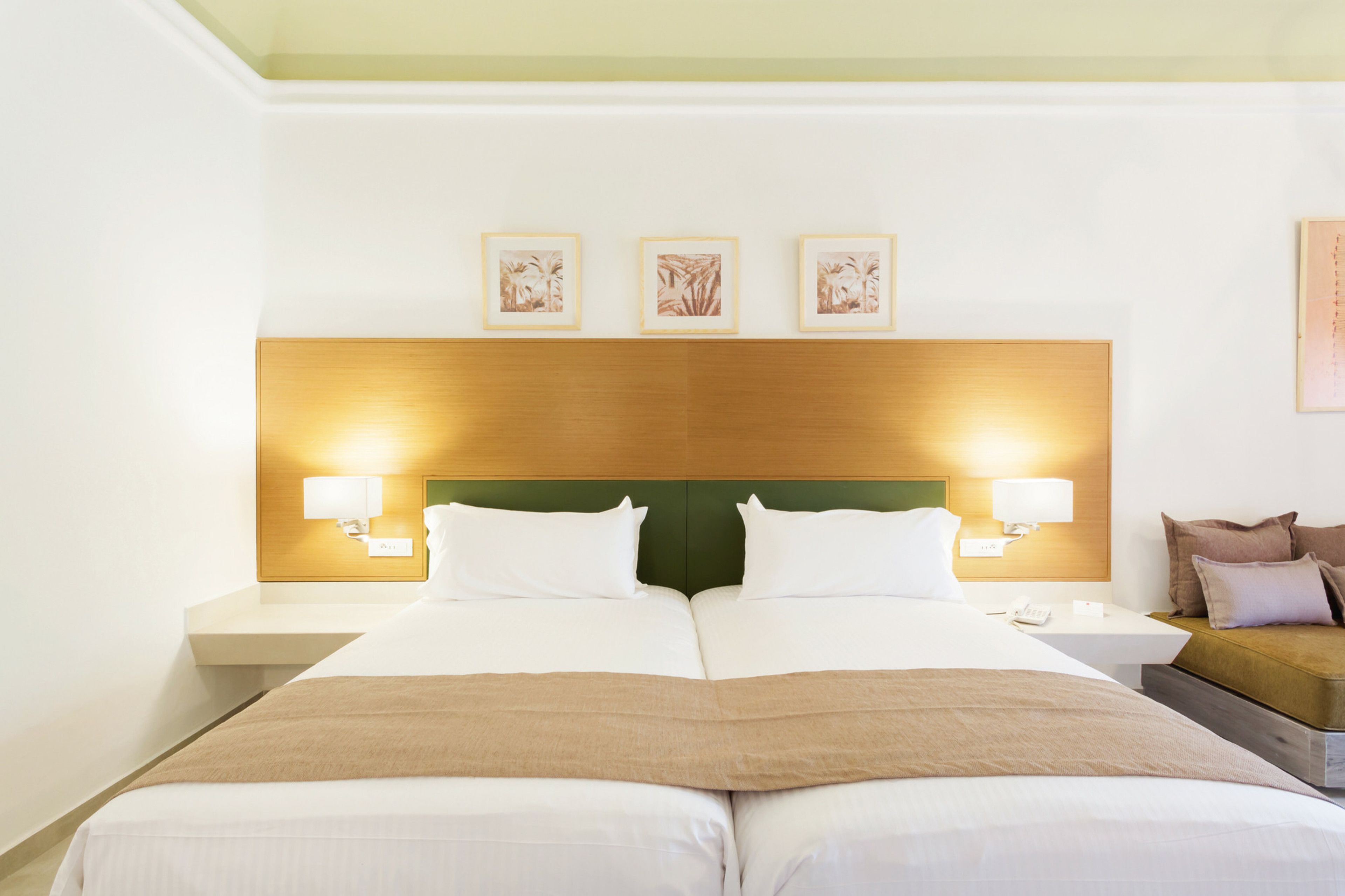 A hotel room with a large bed, two bedside tables, a nightstand, and a sofa.