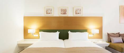 Una habitación de hotel con una cama grande, dos mesitas de noche y un sofá.