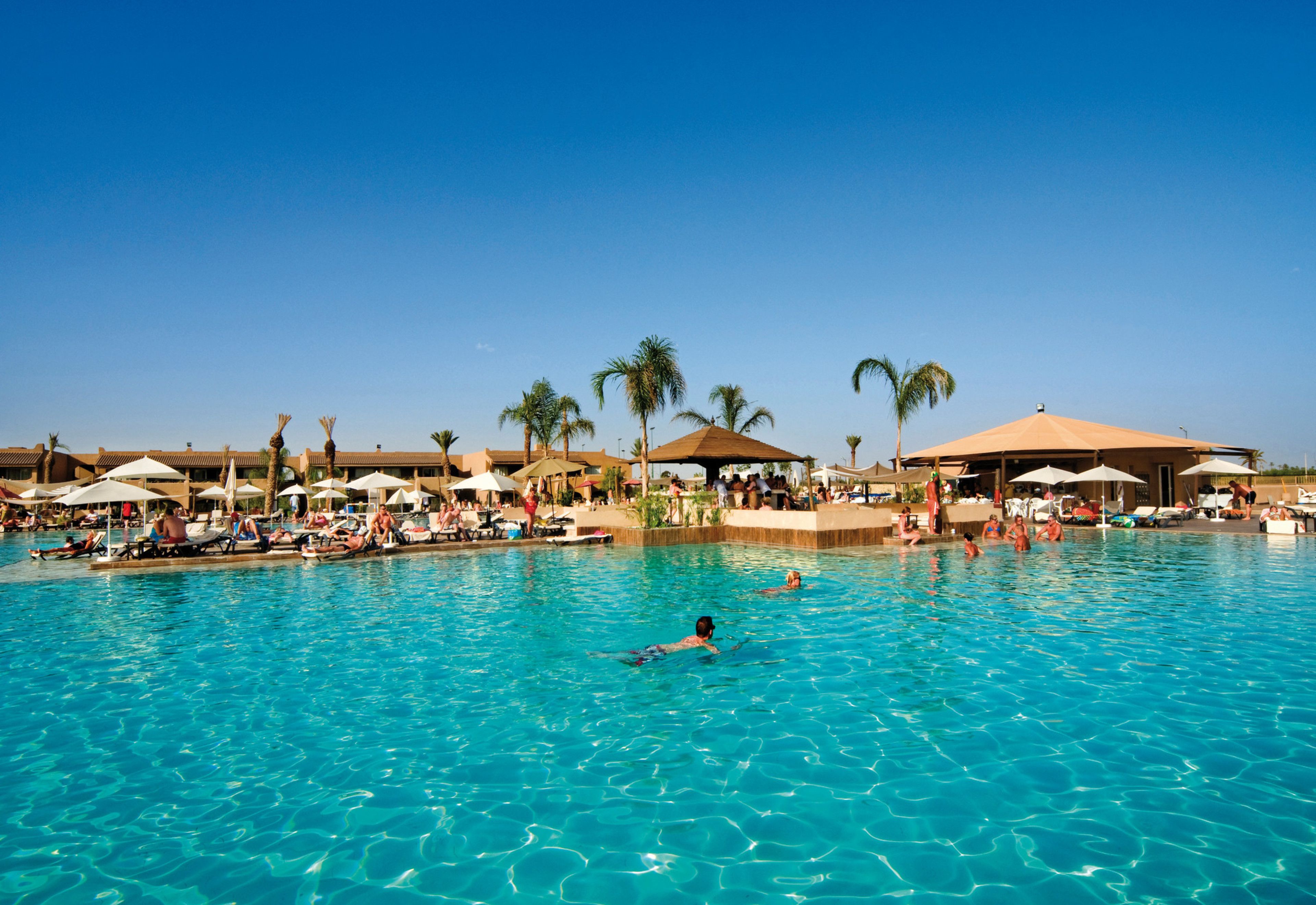 Una piscina techada, una piscina al aire libre, sombrillas
