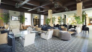 A spacious lobby with modern furniture, large windows, and decorative plants.