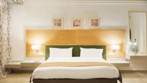 A hotel room with a large bed, two bedside tables, a wooden headboard, and three framed pictures on the wall.