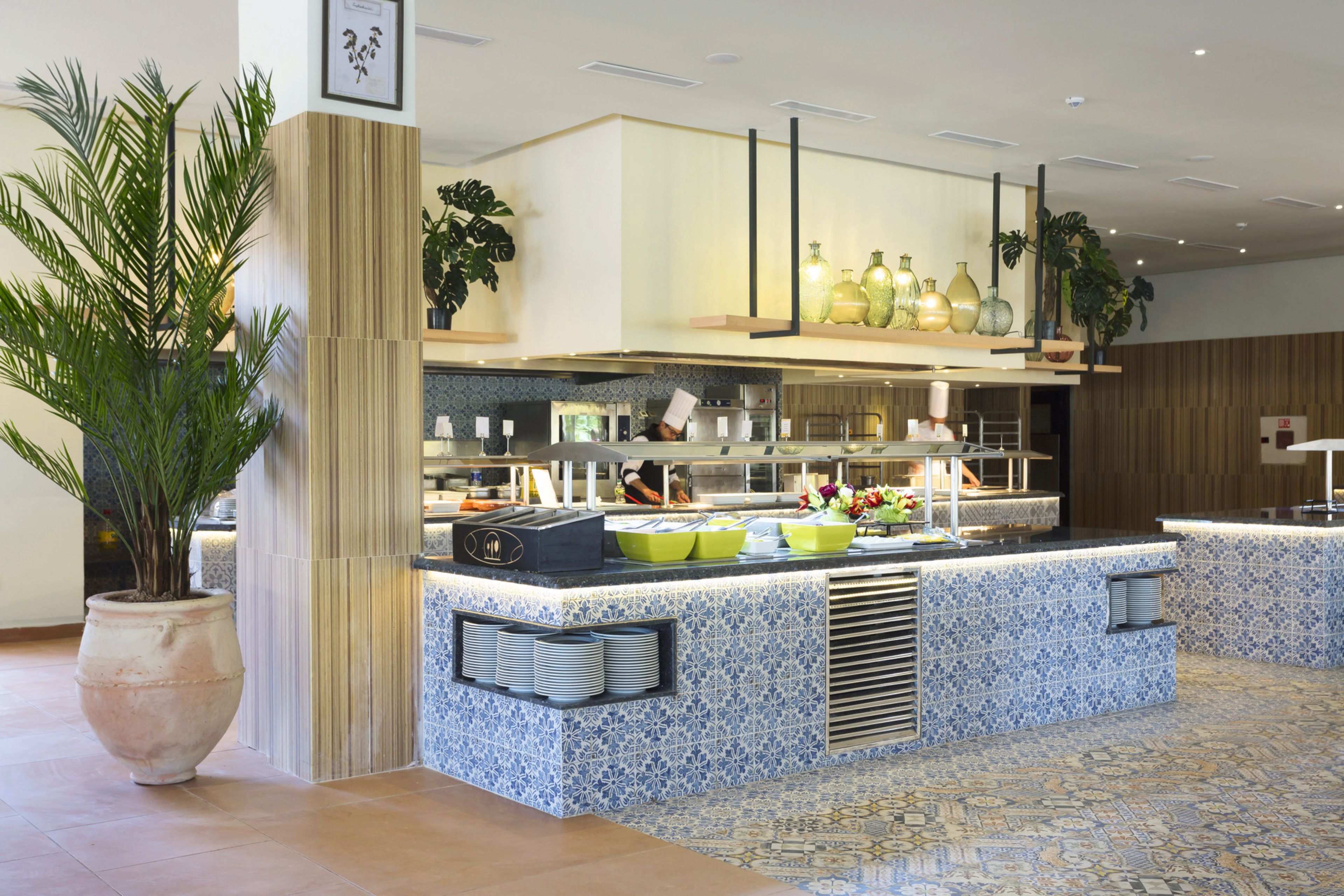 Une cuisine moderne dotée d’un îlot central, d’appareils électroménagers intégrés et d’un revêtement mural décoratif.