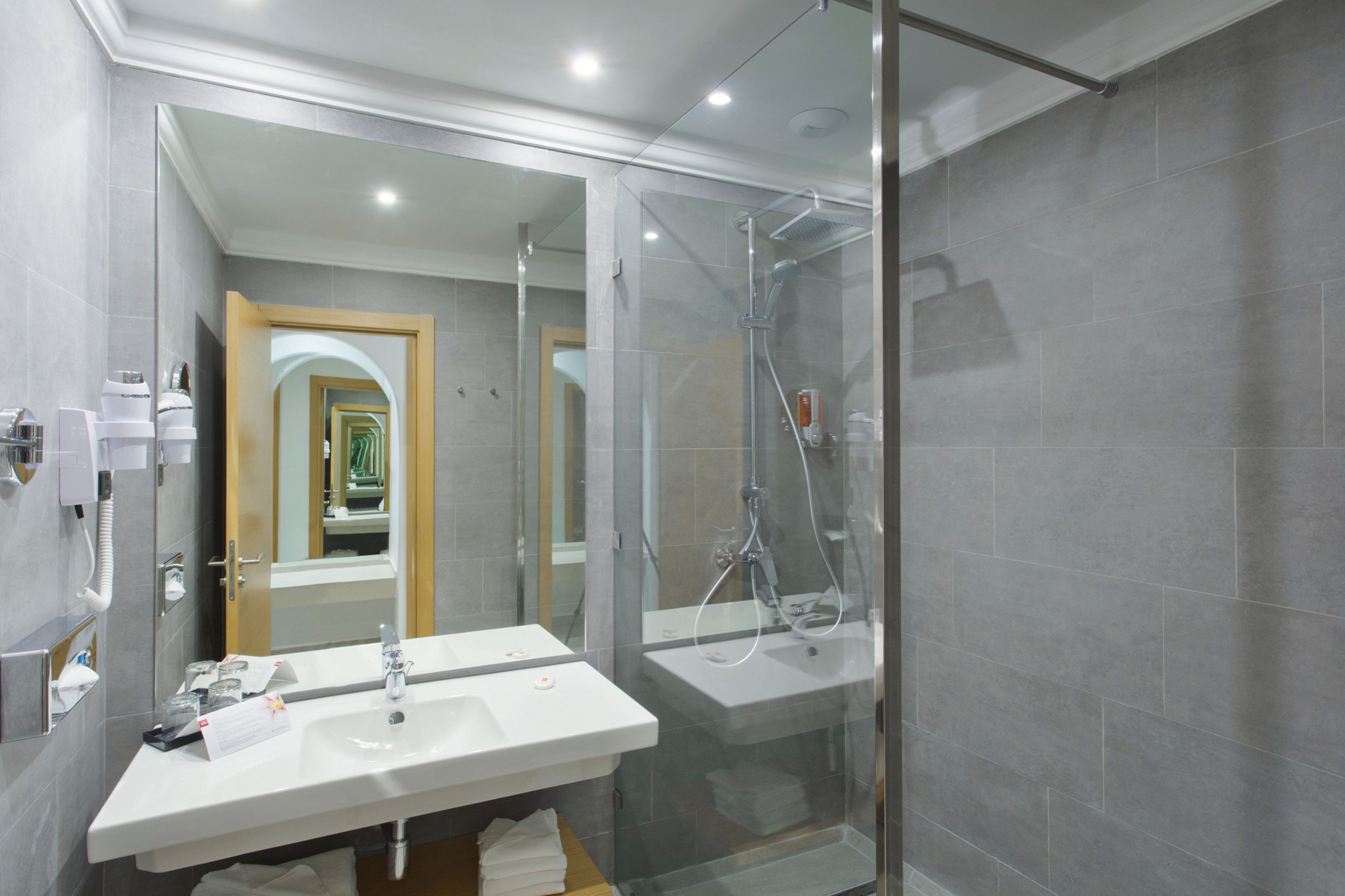 A modern bathroom with a glass-enclosed shower, two sinks, and a mirror.