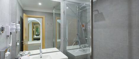 A modern bathroom with a glass-enclosed shower, two sinks, and a mirror.