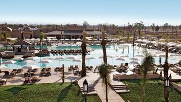 Un resort con varias piscinas, áreas de descanso con sombrillas y palmeras.