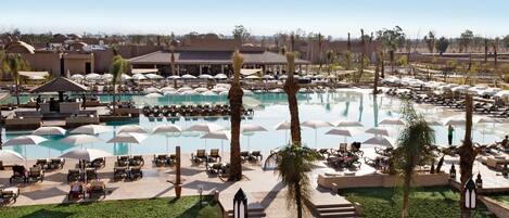A resort with multiple swimming pools, lounge areas with umbrellas, and palm trees.