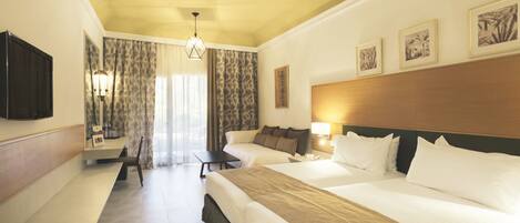 Habitación de hotel con dos camas, un escritorio, una silla, un televisor y obras de arte en las paredes.