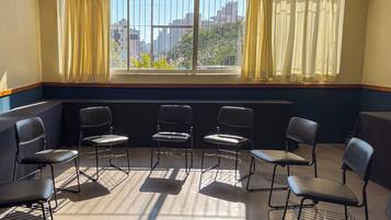 Una habitación con un ventanal grande, cuatro sillas dispuestas en semicírculo y un radiador debajo de la ventana.