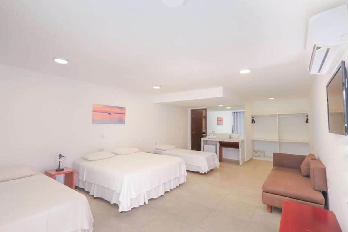 Ein Hotelzimmer mit zwei Betten, einem Schreibtisch, einer Sitzecke und einem durch eine offene Tür einsehbaren Badezimmer.