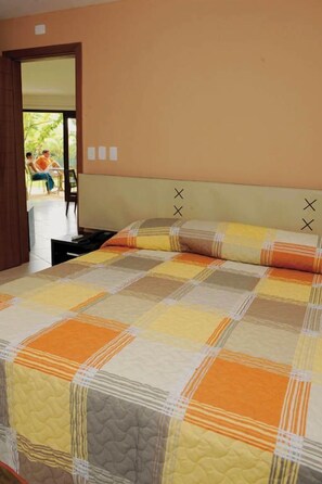 A bedroom with a large bed, a headboard with decorative elements, and a view of an outdoor area with chairs. - Pipa Ocean View (Tibau do Sul)