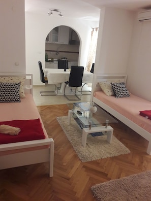 A modern living room with two white sofas, a glass coffee table, and a dining area with a white table and chairs. - Guest House Vlado (Split)