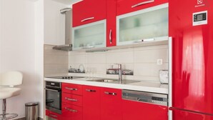 A modern kitchen with red cabinetry, a stainless steel sink, and a dishwasher. - Guest House Vlado (Split)