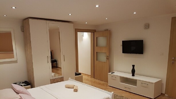 A bedroom with a bed, a wardrobe, a TV, and a small table. - Guest House Vlado (Split)