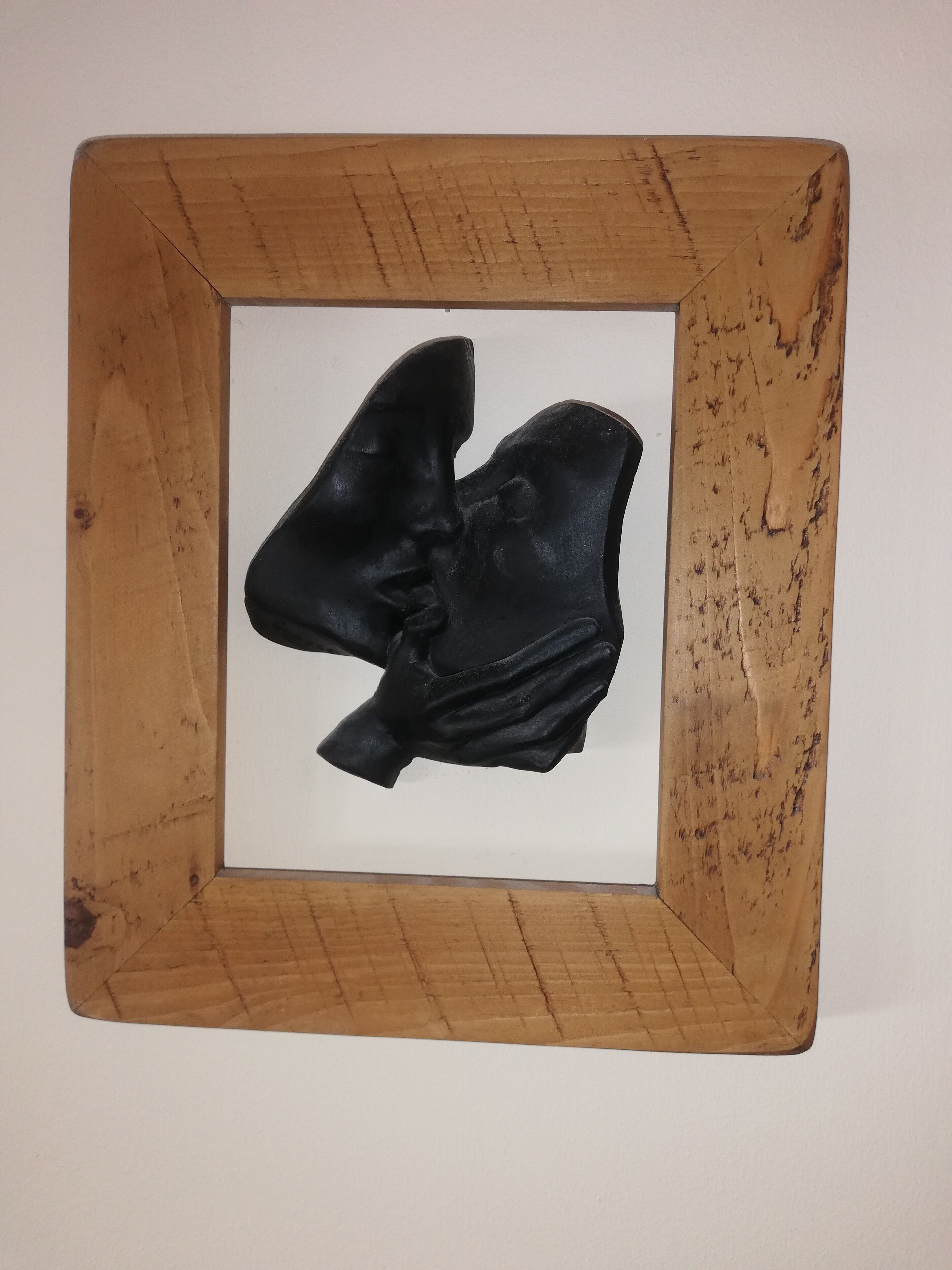 A framed sculpture of a face in profile.