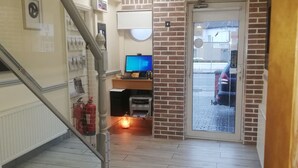 Ein Flur mit Treppe, einer Rezeption, einem Computer und einem Feuerlöscher.