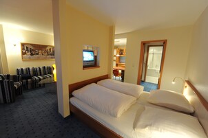 Una habitación de hotel con una cama, un sofá, un televisor y un cuadro en la pared.