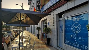 Un café con terraza, piso de baldosas y un cartel que dice 'Juan de Austria'.