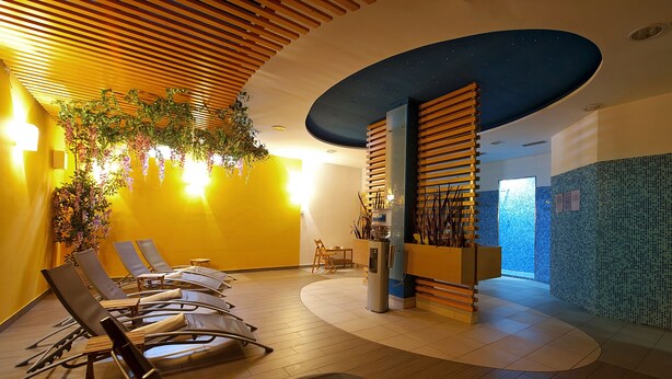 A modern lobby with a curved ceiling, wooden slats, and a seating area with lounge chairs. - Hotel Bajt Maribor (Maribor)