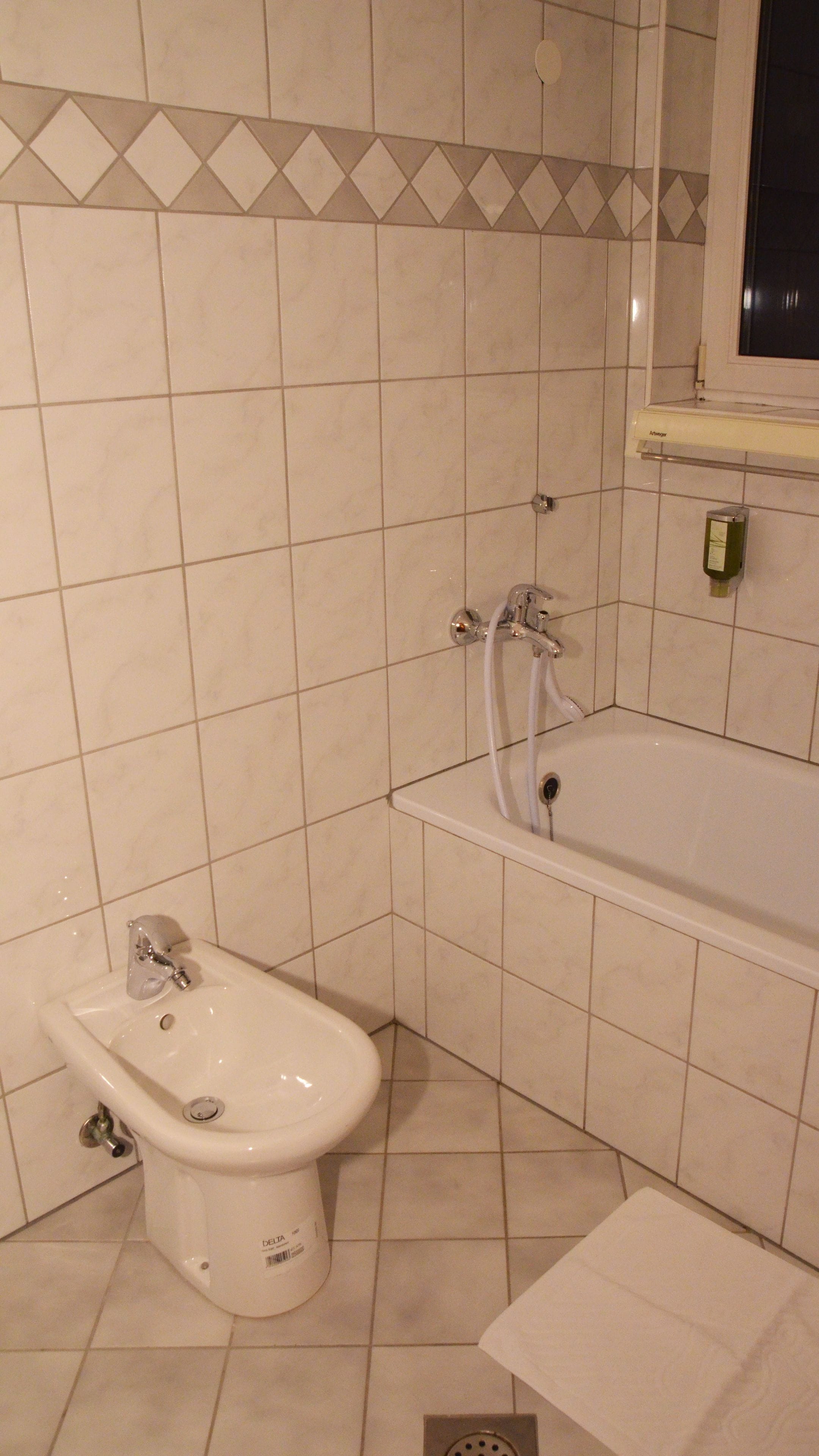Un baño con bidé, bañera y una ventana sobre la bañera.