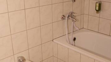 Un baño con bidé, bañera y una ventana sobre la bañera.