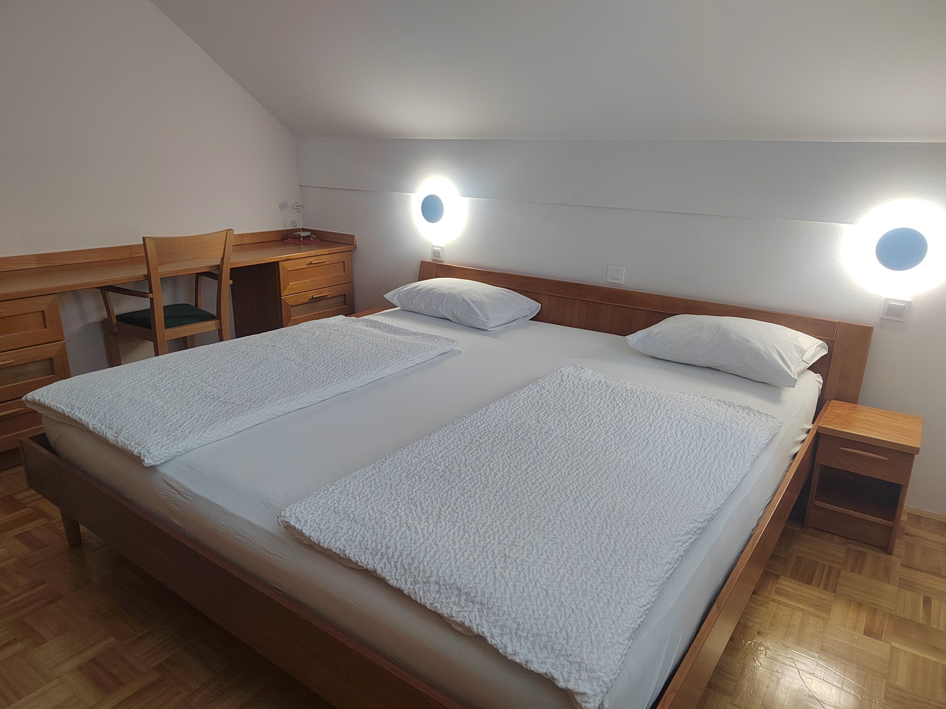 Un dormitorio con una cama grande, dos mesitas de noche, un escritorio de madera y una silla.