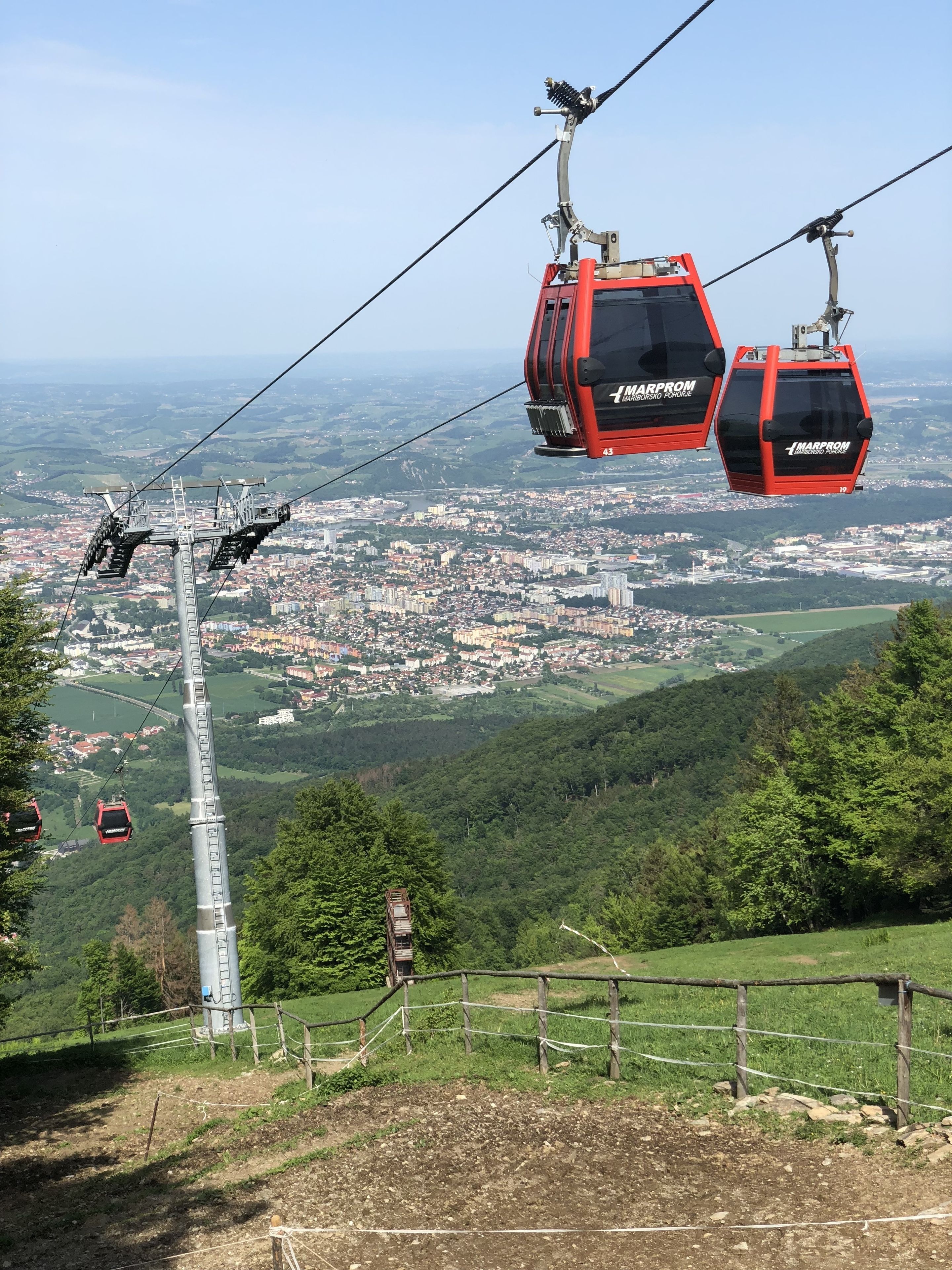 A cable car system with red gondolas labeled "Marprom" and a view of a city below.