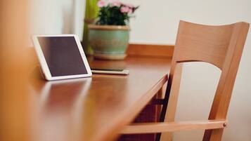 A wooden table with a tablet and a potted plant.