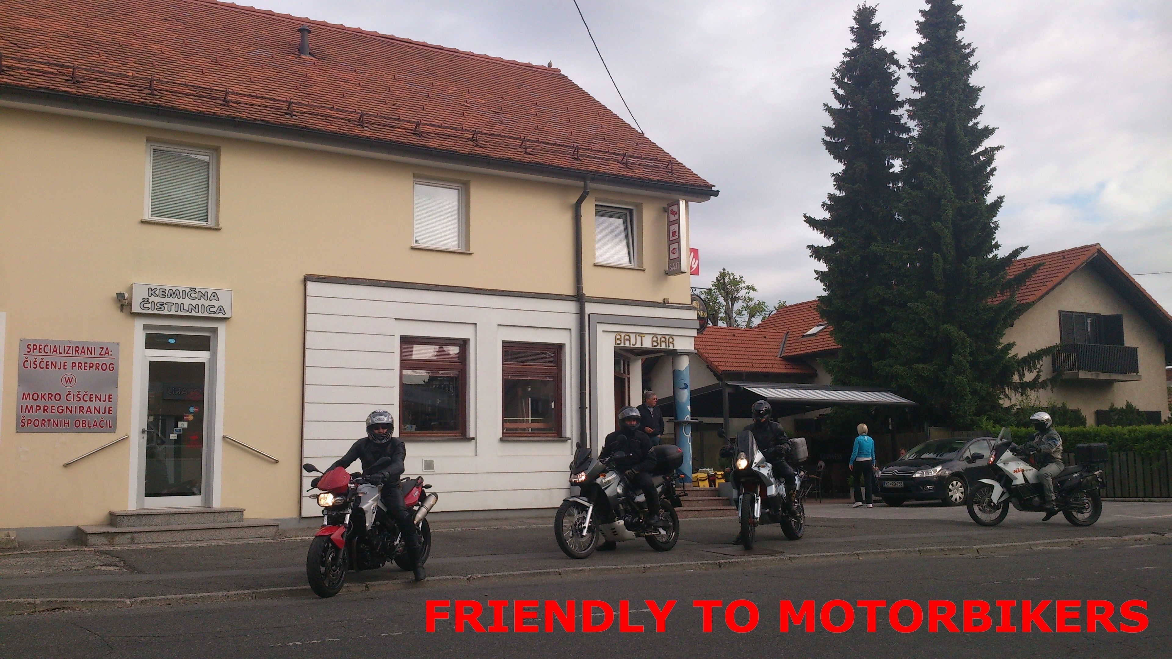 A building with a sign for a bar and a sign for a business offering services for motorcyclists.