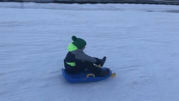 Un niño deslizándose en un trineo por una pendiente nevada.