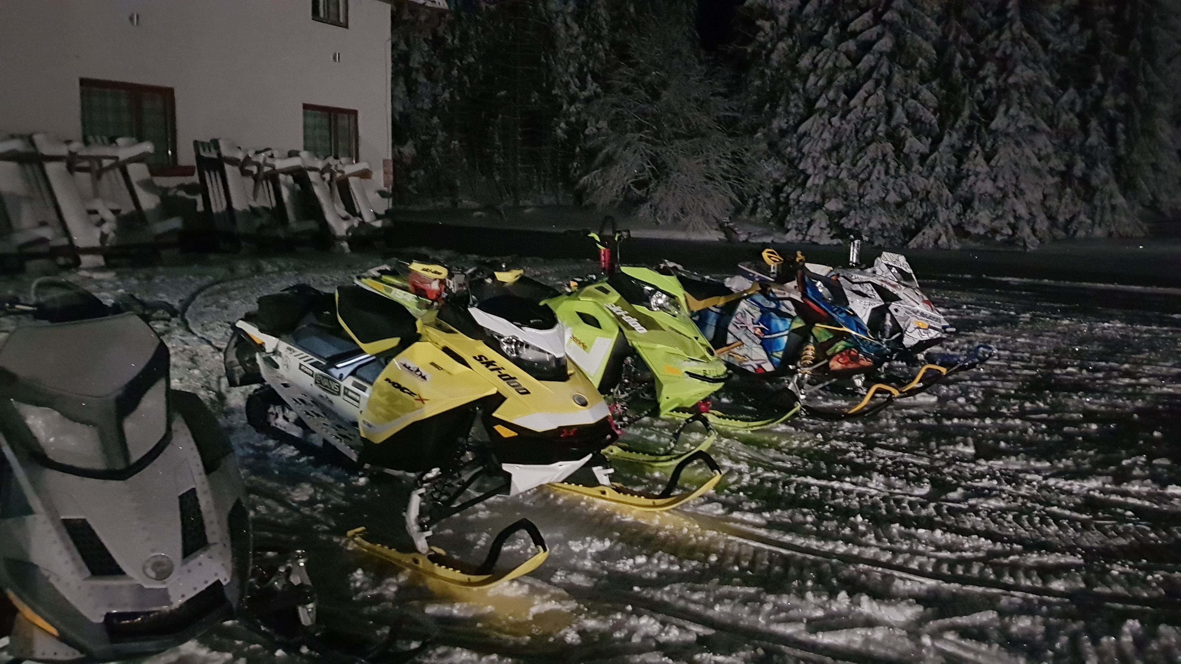 Une rangée de motoneiges est garée sur un sol recouvert de neige.