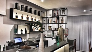 A bar area with shelves of liquor bottles, a bar counter with a computer, and a decorative plant. - Hotel Bajt Maribor (Maribor)