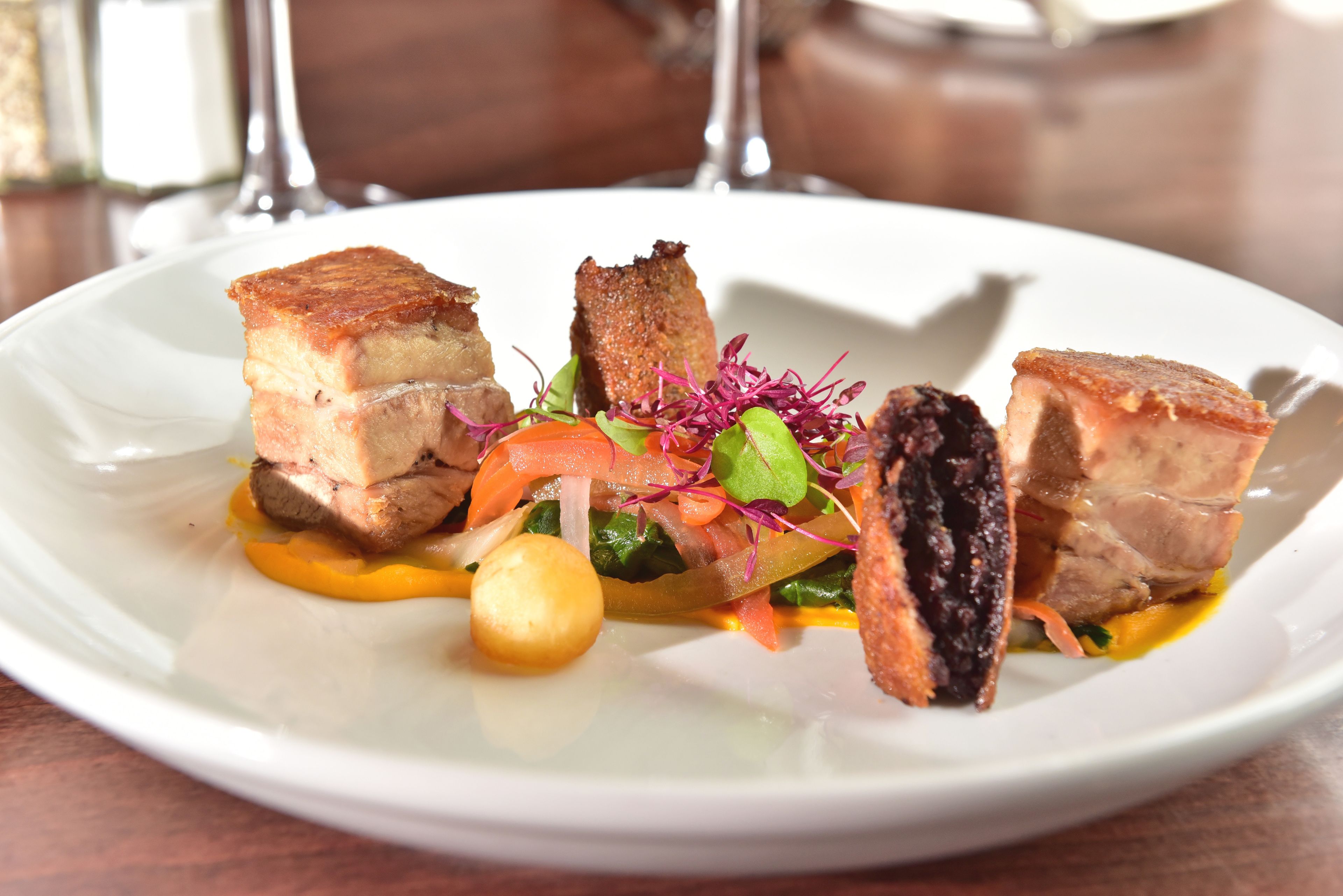 A white plate with a dish of food, including meat and vegetables.