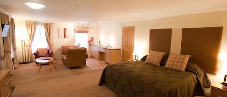 A hotel room with a bed, a desk, a chair, a TV, and a bathroom.